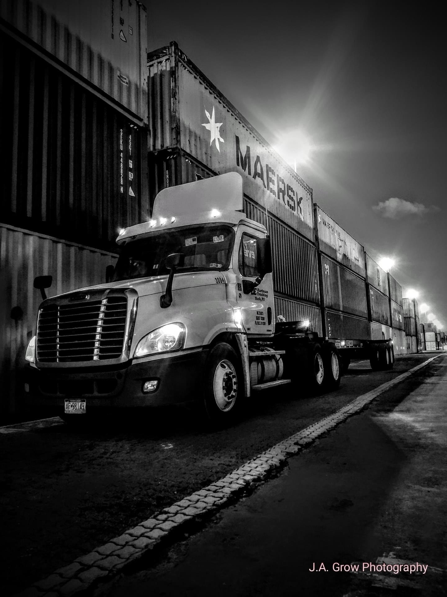 DE Hartman truck beside stacked intermodal containers